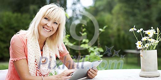 Older woman sitting outside with a tablet computer