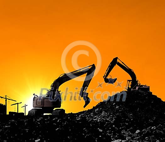 Excavators working on a sunset