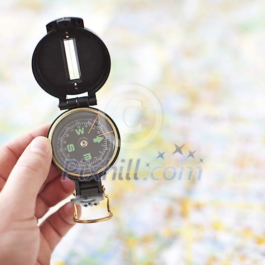 Hand holding a compass on a map background