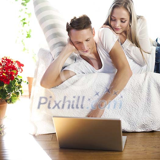 Couple lying on the sofa, looking at the laptop