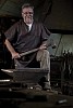 50-year old blacksmith holding a hammer by big anvil