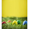 Coloured easter eggs on grass, yellow background