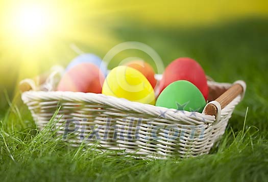Basket on grass full of colorful easter eggs