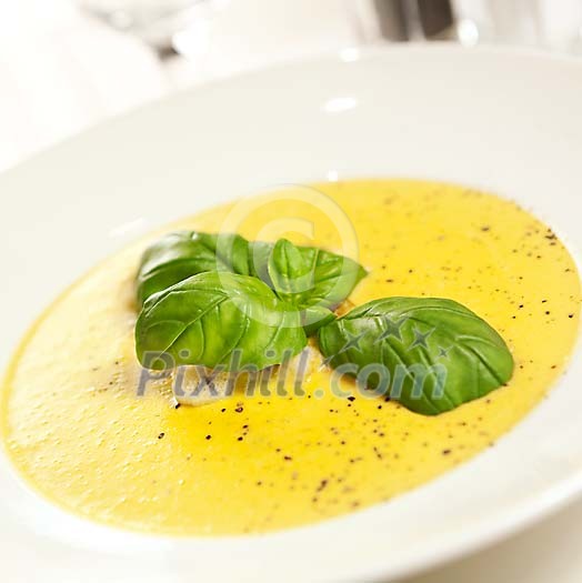 Yellow soup with basilica leaves Yellow soup with basilica leaves