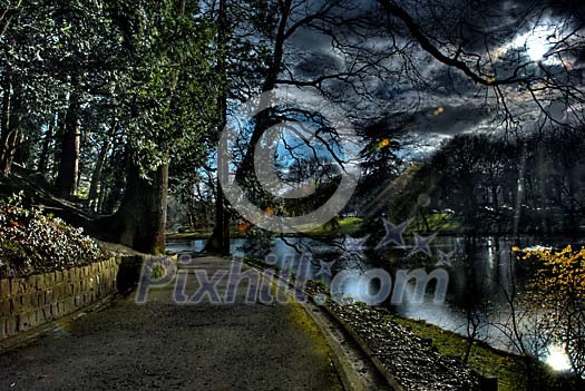 Dark park with moon peeking through the clouds