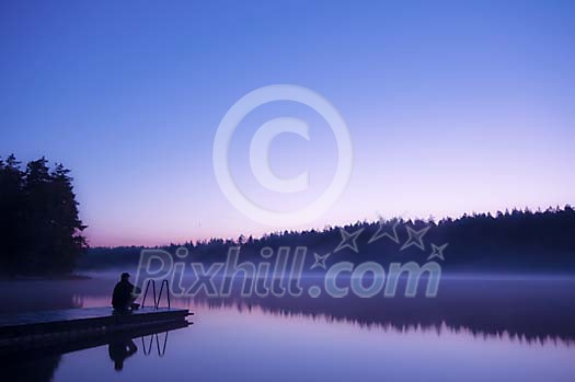 Person sitting on the pier early in the morning Person sitting on the pier early in the morning