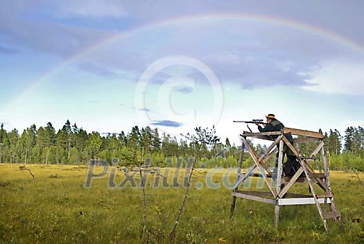 Hunter aiming under the rainbow