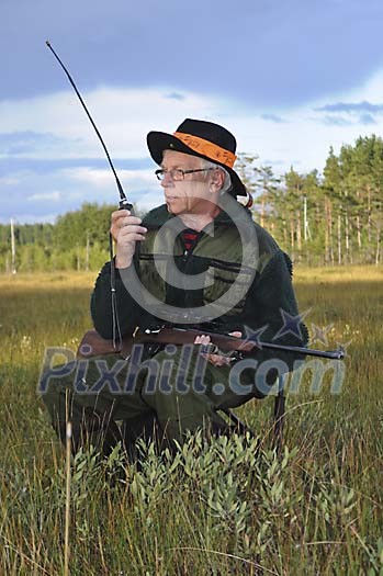 Hunter with a rifle talking in a walkie-talkie