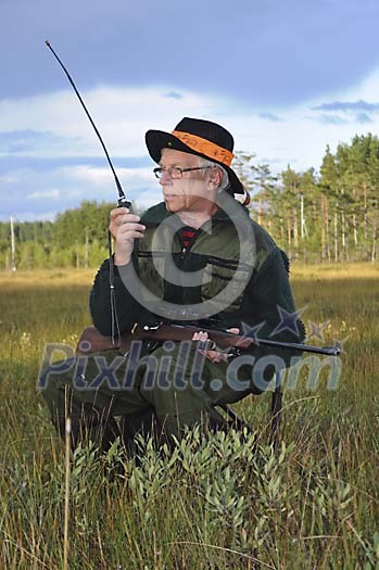 Hunter with a rifle talking in a walkie-talkie Hunter with a rifle talking in a walkie-talkie