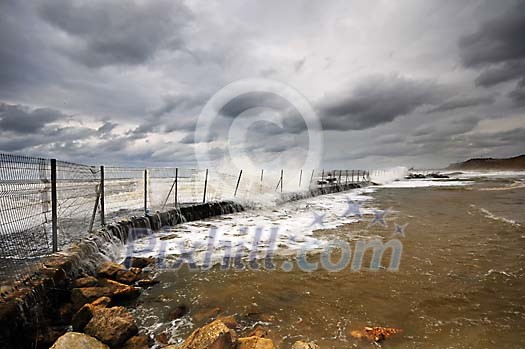 Stormy waves splashing over metallic fence