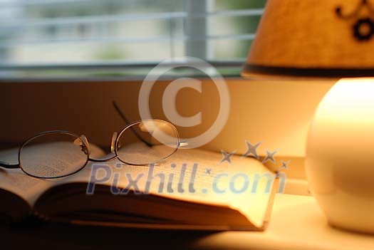 Book and eyeglasses with a lamp