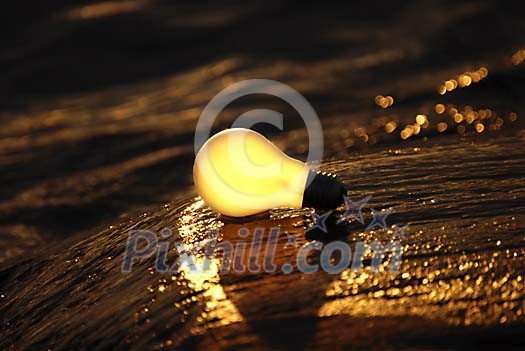 Lightbulb lighted by sun on the rocks Lightbulb lighted by sun on the rocks