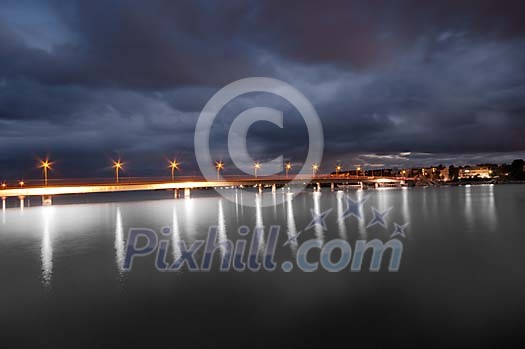 Lighted bridge on the river in the evening