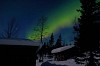 Bright green northern lights over small cottage