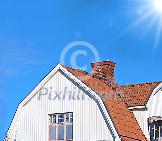 White house with red tiles and a blue sky with sunshine