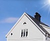 grey wooden house with black tin roof and a blue sky with sunshine