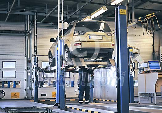 Mechanic working under a elevated car in a garage Mechanic working under a elevated car in a garage