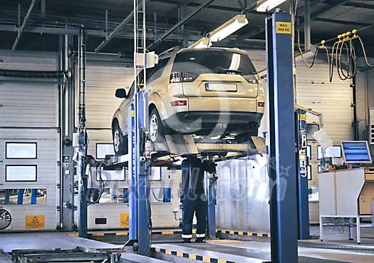 Mechanic working under a elevated car in a garage