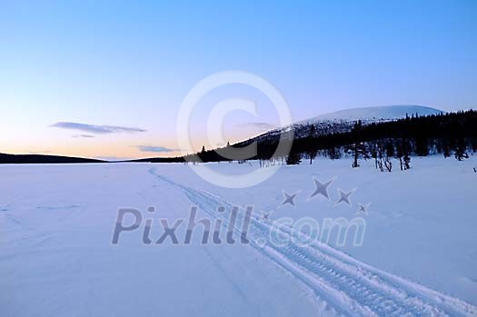 Tracks on arctic lake at sunset