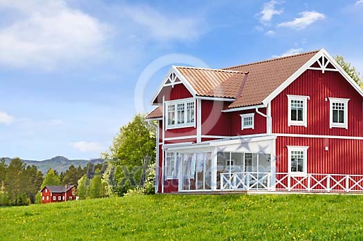 A red wooden house on a green field