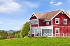 A red wooden house on a green field