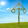 May pole or midsummer pole on a green field and a blue sky with sunshine 