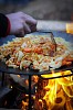 Hand mixing food on a campfire pan