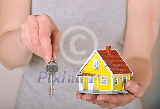 Human hand holding a house and a key to the house