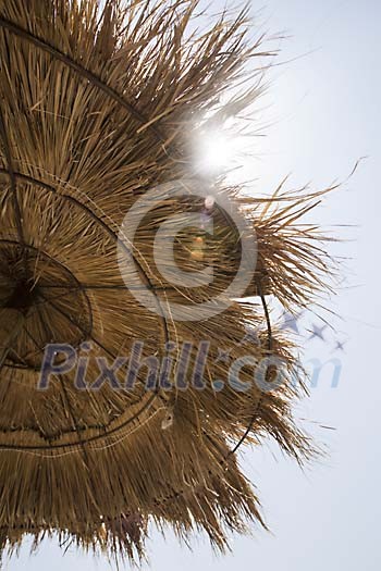 Sun shining over a straw parasol Sun shining over a straw parasol