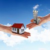 Human hand against blue sky background and house