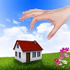 Human hand against blue sky background and house