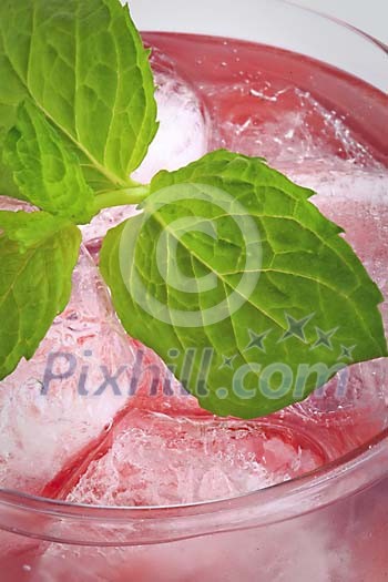 Close up of a pink drink with ice cubes and mint leaves