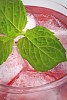 Close up of a pink drink with ice cubes and mint leaves