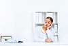 Young woman in business wear sitting with a phone in office