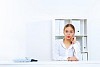 Young woman in business wear sitting with a phone in office