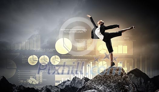 young businesswoman standing on one leg atop of mountain against diagram background