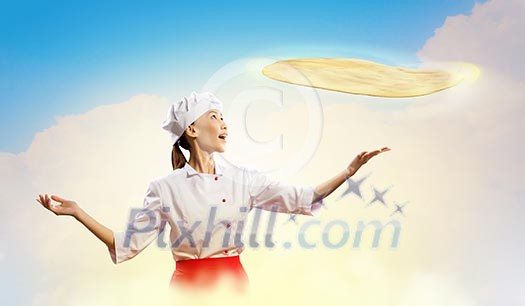 Asian female cook making pizza standing against color background Asian female cook making pizza standing against color background