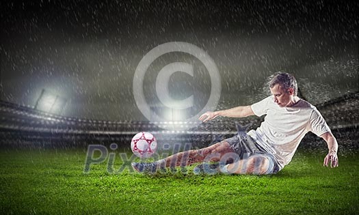 Football player in white shirt striking the ball at the stadium under the rain