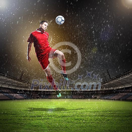 football player in red shirt striking the ball at the stadium under rain