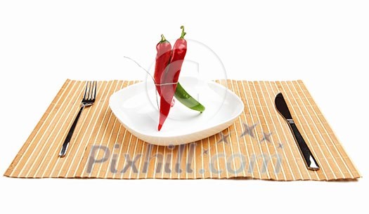 Bright red and bright green chilli pepper rolled into a bun on a white background on a white plate on the table Bright red and bright green chilli pepper rolled into a bun on a white background on a white plate on the table