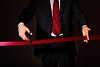 Hand of a businessman with scissors cuting a red ribbon