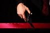 Hand of a businessman with scissors cuting a red ribbon