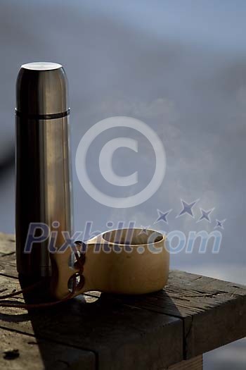 Coffee cup with a thermos on the terrace table