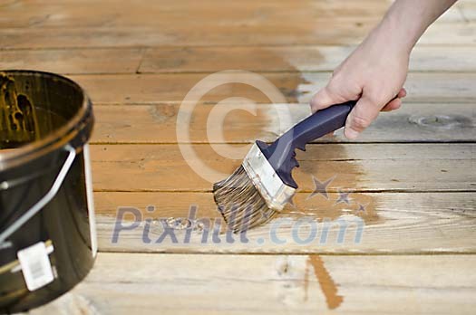 Male hand with a brush painting the floor