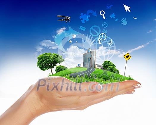 human hand holding a city on green grass hill