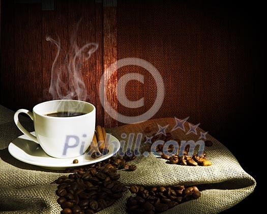 Steaming cup of coffee, cinnamon sticks and a few coffee beans. still life Steaming cup of coffee, cinnamon sticks and a few coffee beans. still life