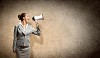 businesswoman in grey suit screaming into megaphone