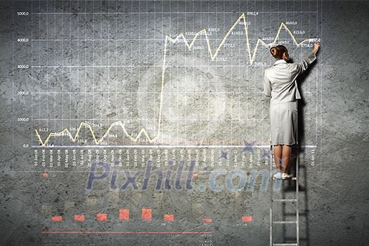 businesswoman standing on ladder drawing diagrams and graphs on wall businesswoman standing on ladder drawing diagrams and graphs on wall