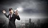 Young businessman in black suit screaming into megaphone