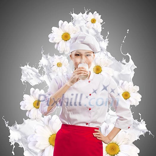 Asian female cook against milk splashes in red apron against flower background drinking milk
